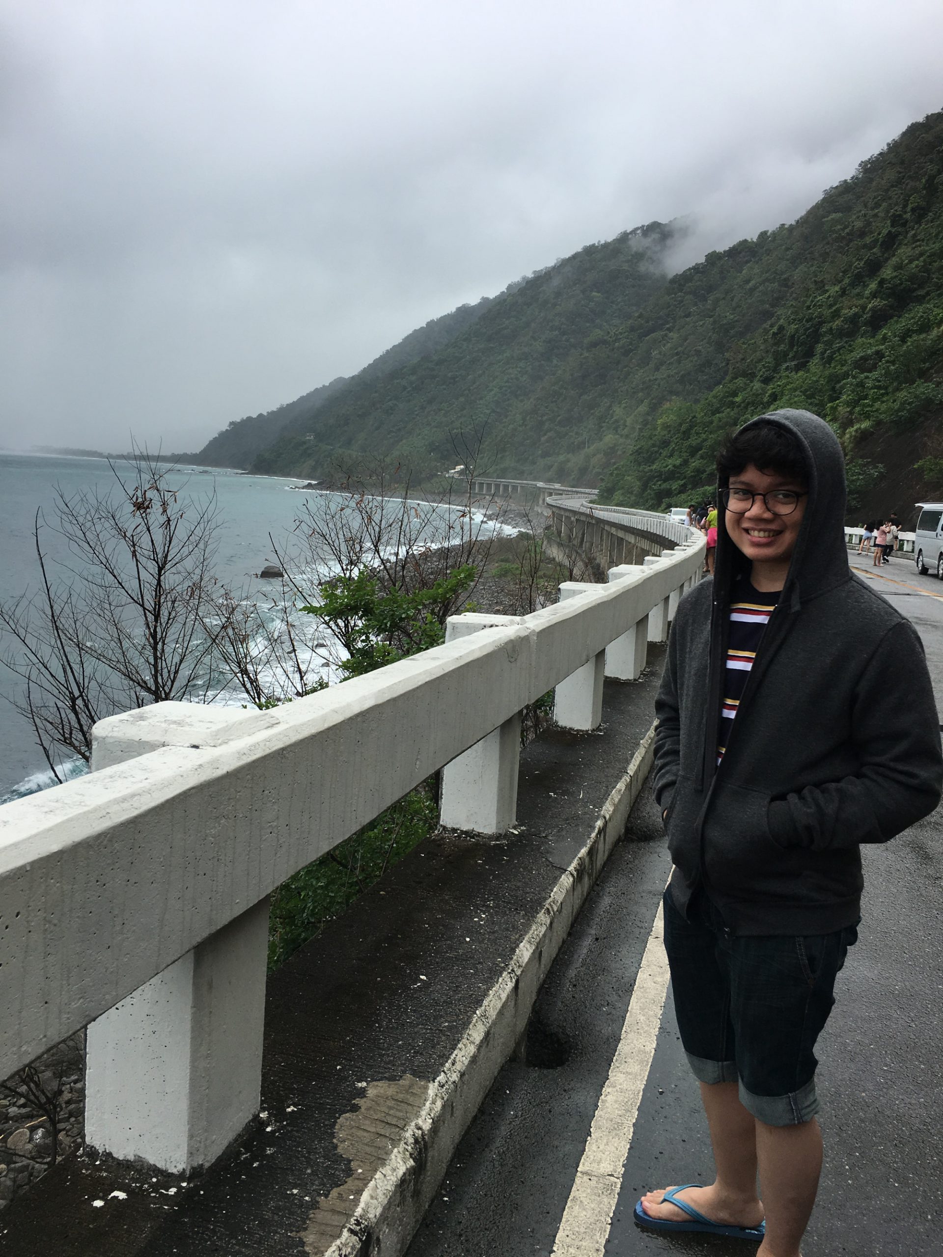 cloudy weather, mountain on the background and a man standing beside the railings